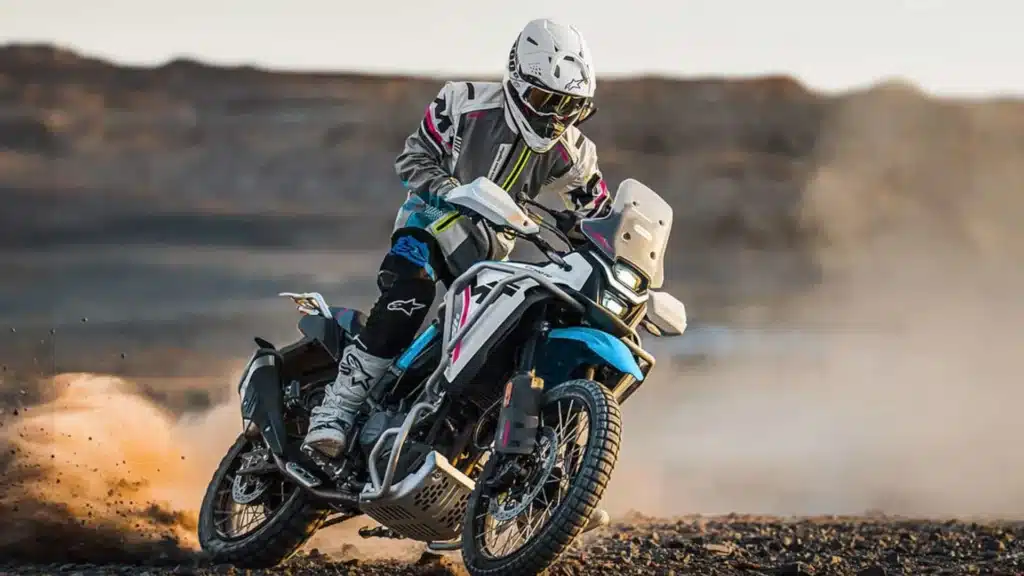 Motociclista conduz uma CFMOTO Ibex 450 azul em terreno de terra.
